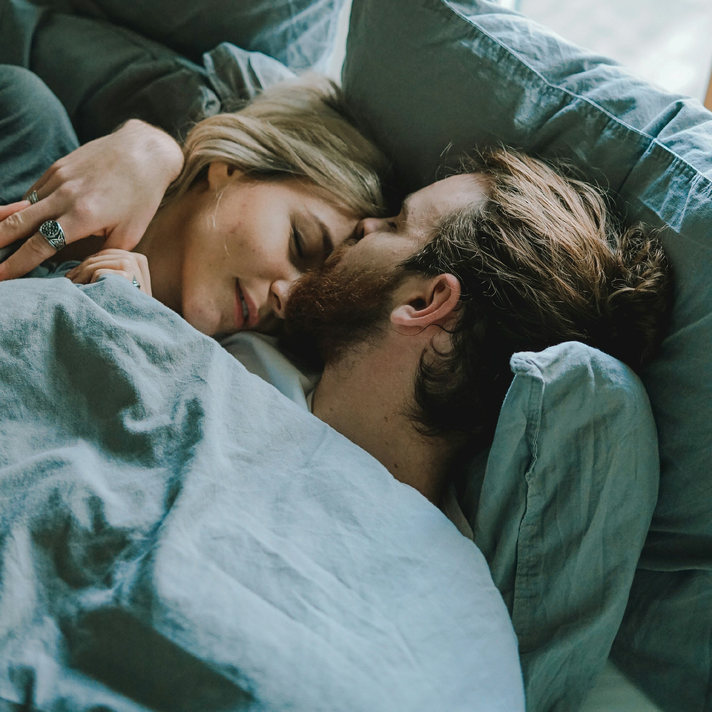 Couple cuddling in bed, sharing a quiet moment of intimacy and emotional connection.