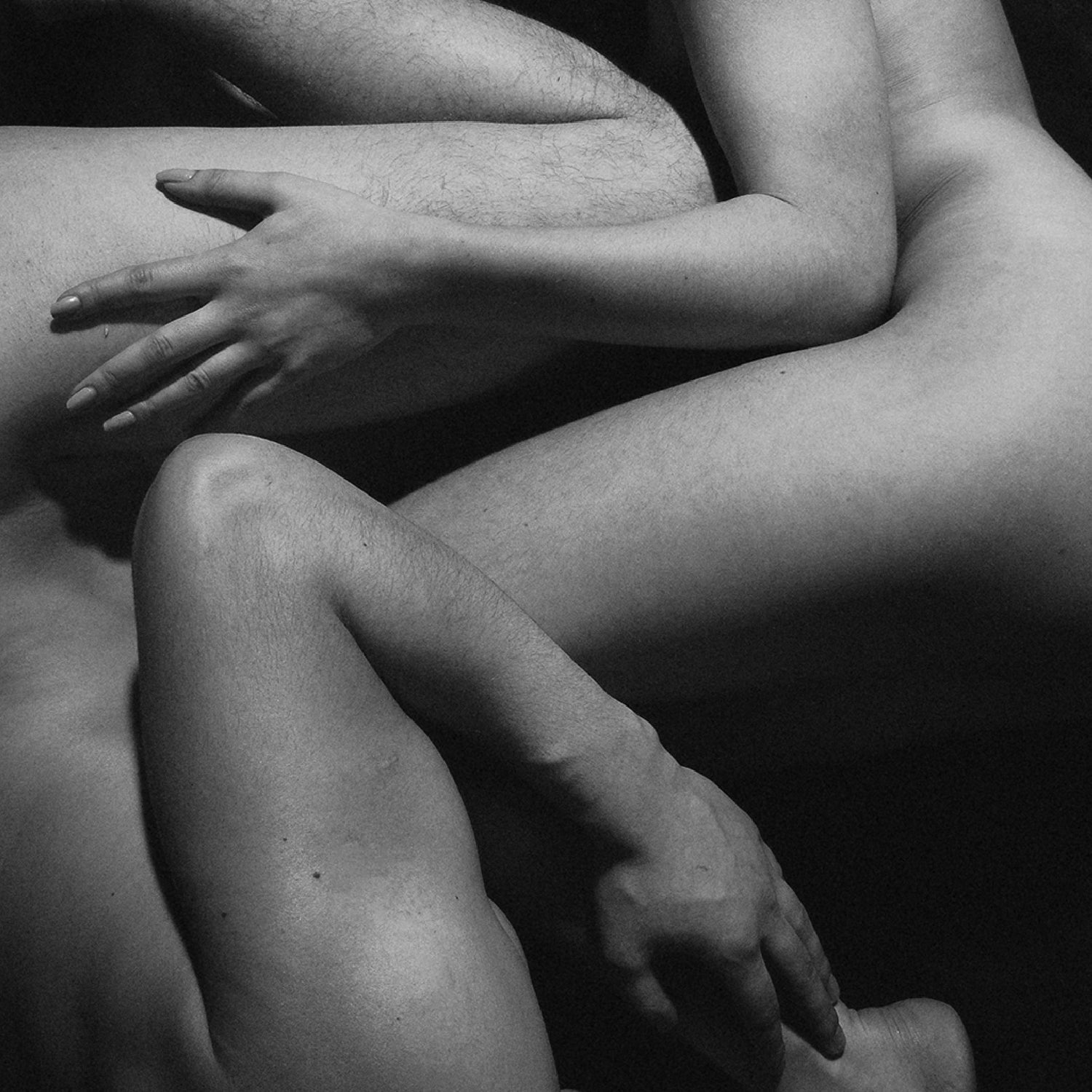 Intertwined nude bodies in an intimate, artistic pose, evoking connection and presence.