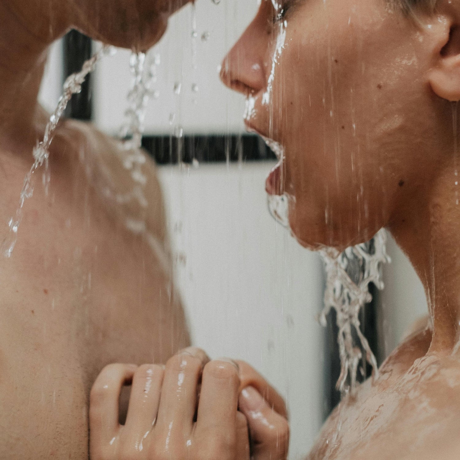 Casal íntimo debaixo do duche, em momento sensorial de conexão e presença.